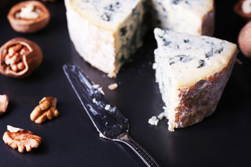Blue cheese with nuts and blade on metal tray background