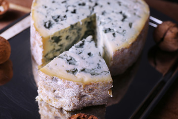 Blue cheese with nuts on metal tray and wooden table background