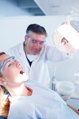Fototapeta premium Dentist examining a patients teeth in chair under bright light