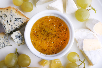 Different sort of cheese with grape and saucer on plate,