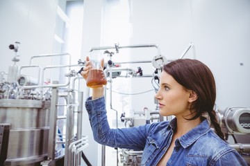 Stylish brunette in denim jacket looking at beaker of beer