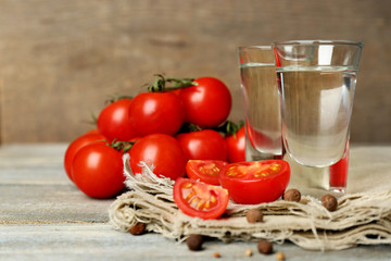 Glasses of ouzo and tomatoes on wooden table