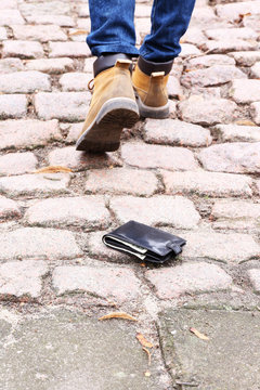 Lost leather wallet and walking male legs, outdoors