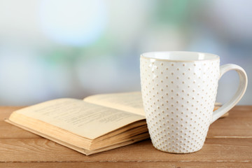 Cup of tea and book on table, on bright background