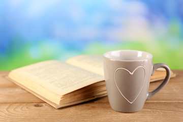 Cup of tea and book on table, on bright background