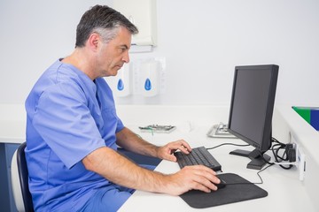 Serious dentist sitting and using computer