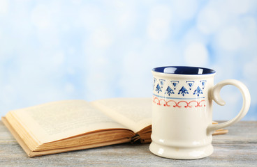 Cup of tea and book on table, on bright background