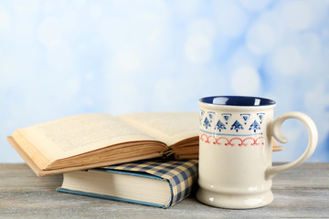 Cup of tea and books on table, on bright background