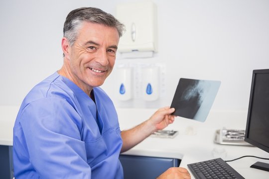 Portrait of a smiling dentist holding x-ray