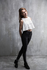 Fototapeta premium Fashionable young girl standing on a gray background textured wa