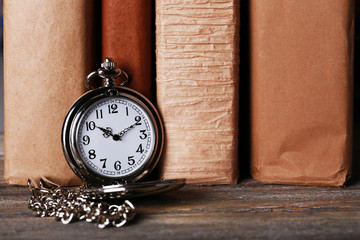 Silver pocket clock on books background