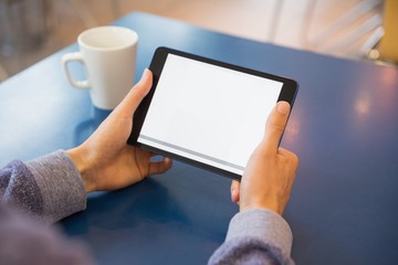 Young student using his tablet in cafe