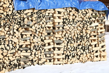 Woodshed with pieces of wood piled up for the winter and snow