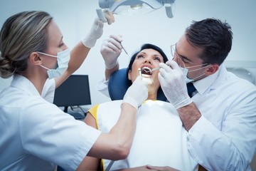 Dentist with assistant examining womans teeth