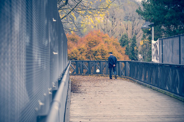 uomo anziano passeggia su un ponte in autunno