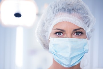 Dentist in surgical mask and cap looking at camera