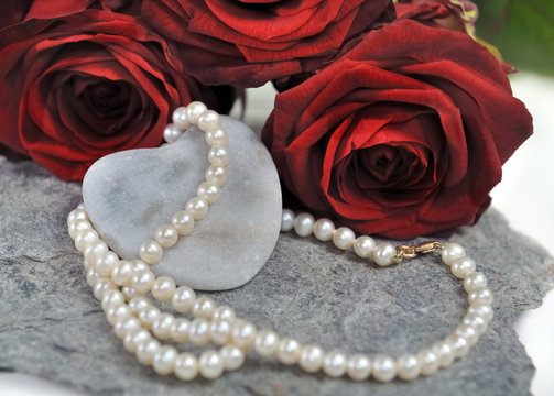 collier de perles sur cœur et roses rouges