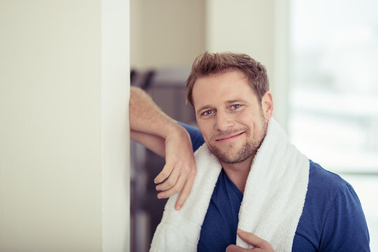 sportlicher mann lehnt im fitness-studio an der wand