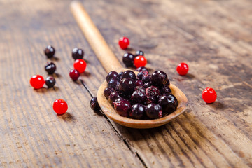 black currant in wooden spoon on rustic background