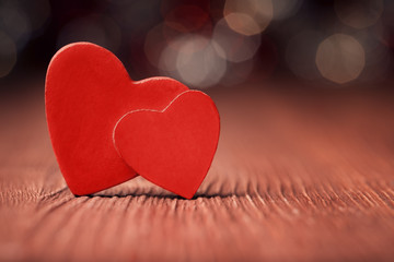 Fototapeta premium Close up of two red hearts on old wooden board against defocused