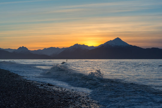 A surfer paddles out in waves on Kachemak Bay
