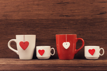 Cups with heart shapes over vintage wooden background