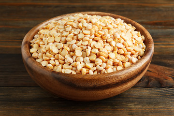 Dry peas in a wooden bowl on wood closeup