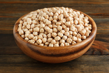Chickpeas in a wooden bowl on wood closeup