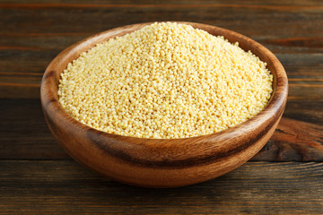 Millet in a wooden bowl on wood closeup