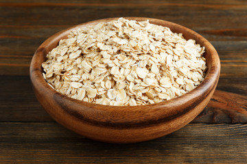 Rolled oats in a wooden bowl on wood closeup