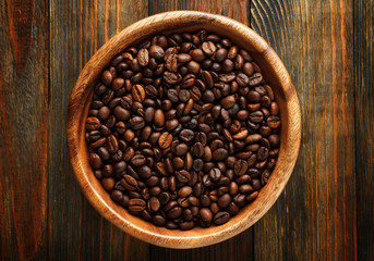 Fototapeta premium Wooden bowl with a coffee beans on wood close up
