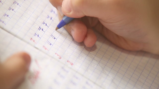Little pupil write digits in square grid notebook
