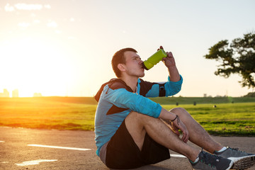 sportsman sitting on the road and drinking water