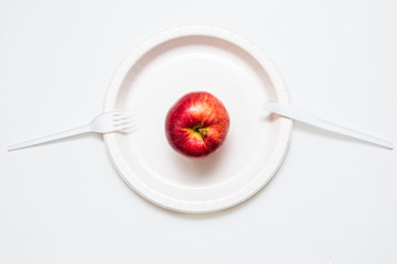 Red apple on white plate with knife and fork