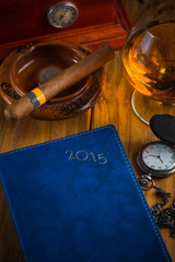 wealthy man desk with cigars, vintage watch cognac and year plan