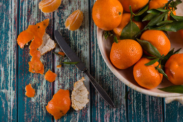 Peeling freshly picked clementines with knife on rustic table