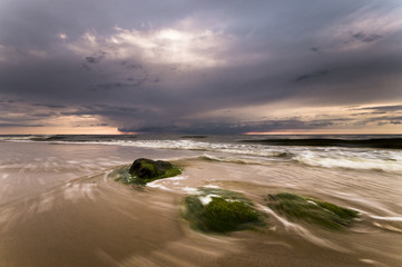 Głazy na morskiej plaży,w oddali przechodząca burza © Mike Mareen