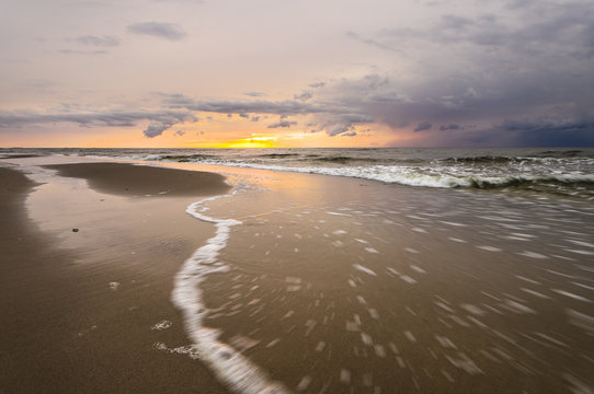 Fototapeta Przybój fali podczas zachodu słońca nad morzem