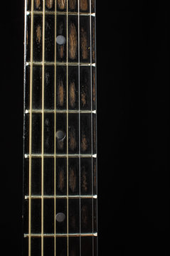 Acoustic guitar fretboard isolated on the dark background