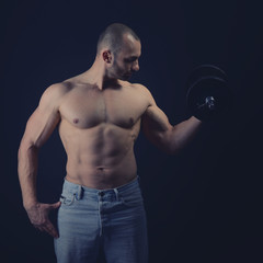 Fototapeta na wymiar Strong athletic man with perfect body posing with dumbbells