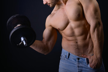 Fototapeta na wymiar strong athletic man with perfect body posing with dumbbells on b
