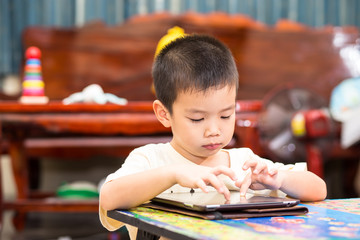 Little handsome boy touch on ipad tablet and playing game at hom