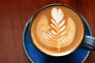 cup of latte art coffee on wooden background