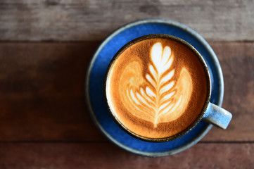 cup of latte art coffee on wooden background