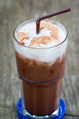 Iced milk chocolate with straw on wood table