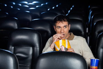 Obraz premium Man Eating Popcorn While Watching Movie In Theater
