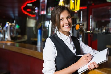 Happy barmaid writing in notepad