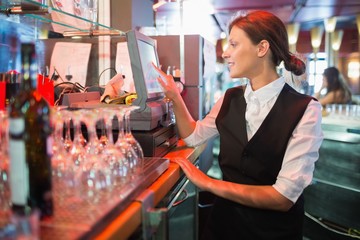 Happy barmaid using touchscreen till