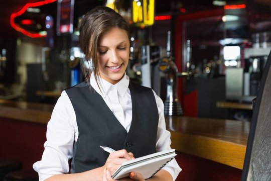 Happy barmaid writing in notepad - Powered by Adobe