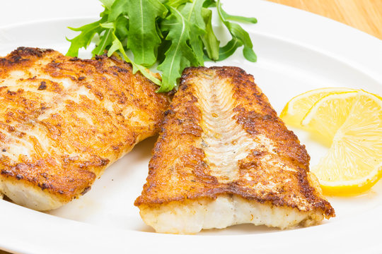 White fish with lemon on white plate